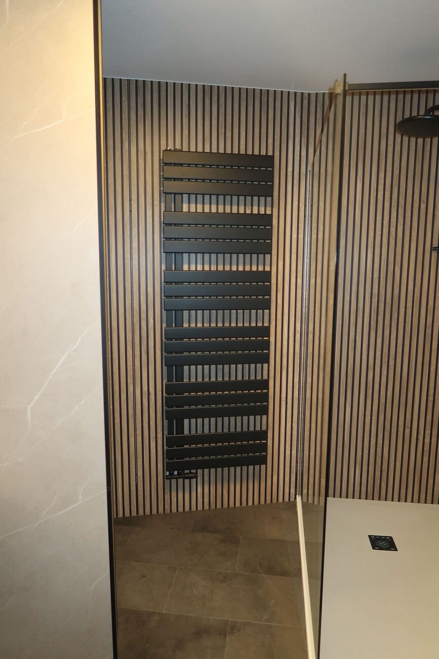 Moderne badkamer met houten lattenwand en zwarte handdoekradiator