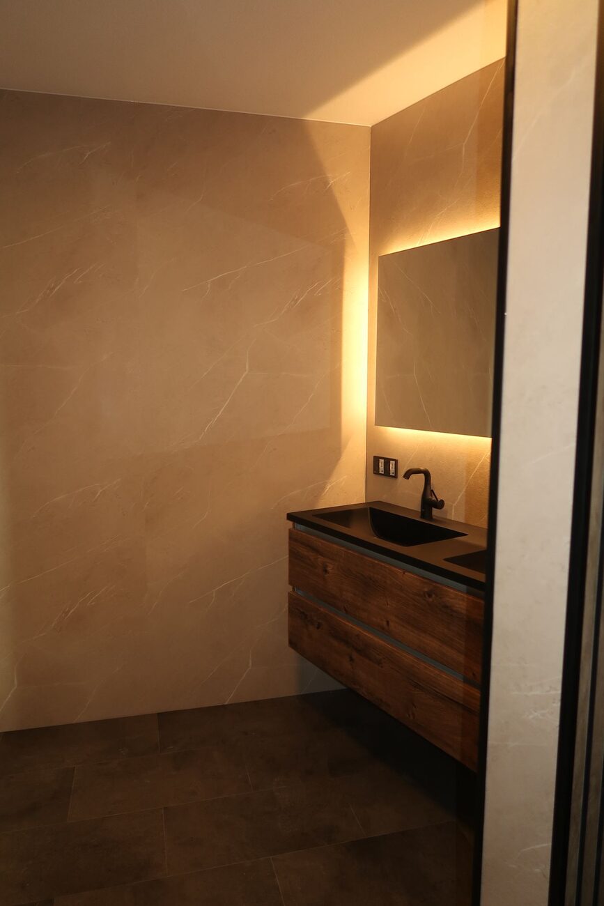 Moderne badkamer met houten wastafelmeubel en verlichte spiegel