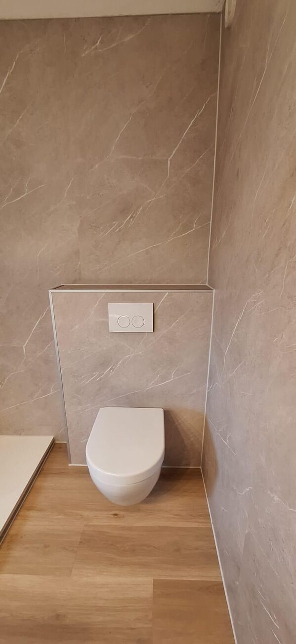 Gerenoveerd toilet met marmerlook wandtegels en houtlook vloer